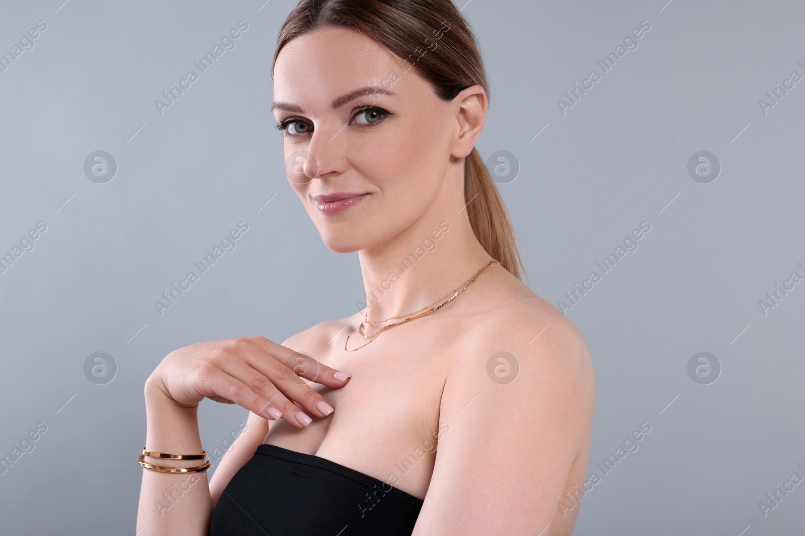 Photo of Beautiful woman with elegant jewelry on light grey background