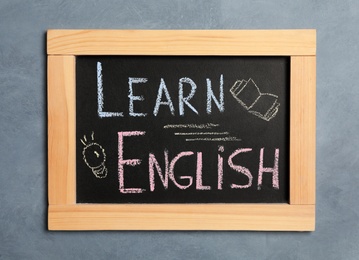 Photo of Blackboard with phrase Learn English on grey background, top view