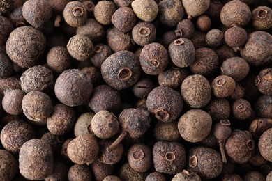 Black pepper grains as background, top view