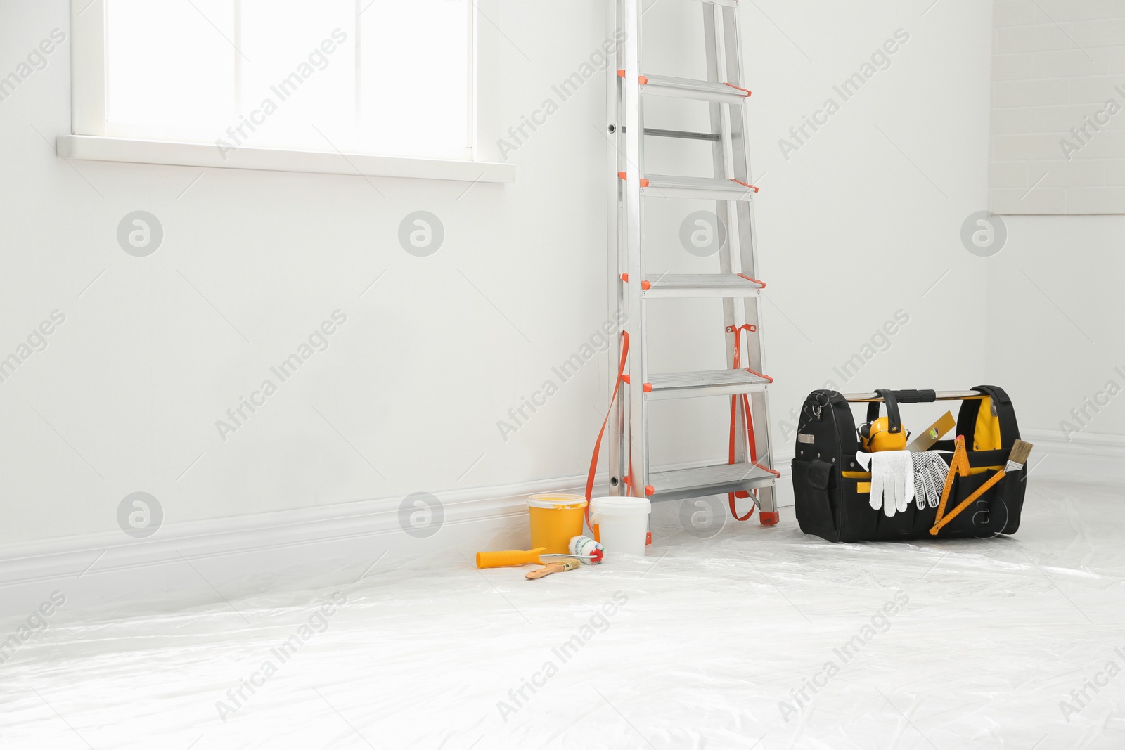 Photo of Stepladder and different tools near wall in room. Interior renovation