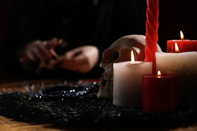 Photo of Soothsayer at table indoors, focus on skull and candles