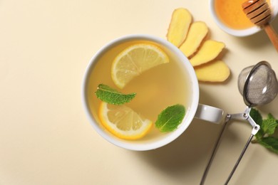 Delicious ginger tea and ingredients on beige background, flat lay