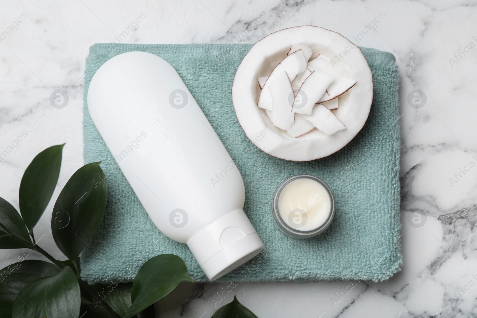 Photo of Body cream and cosmetic product, coconut with towel on white marble table, flat lay