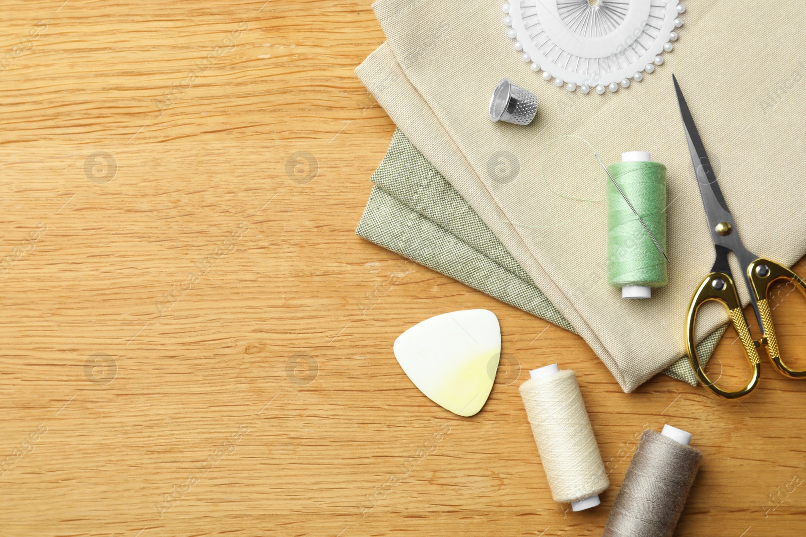 Photo of Flat lay composition with spool of threads and sewing tools on wooden table. Space for text