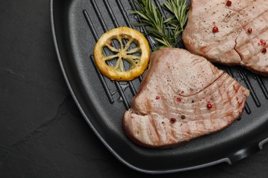 Delicious tuna steaks, lemon and rosemary on black table, top view