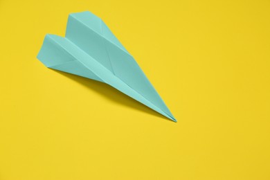 Light blue paper plane on yellow background, space for text