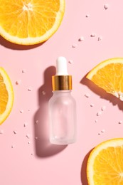 Bottle of cosmetic serum and orange slices on pink background, flat lay