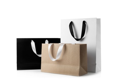 Photo of Paper shopping bags with ribbon handles on white background. Mockup for design