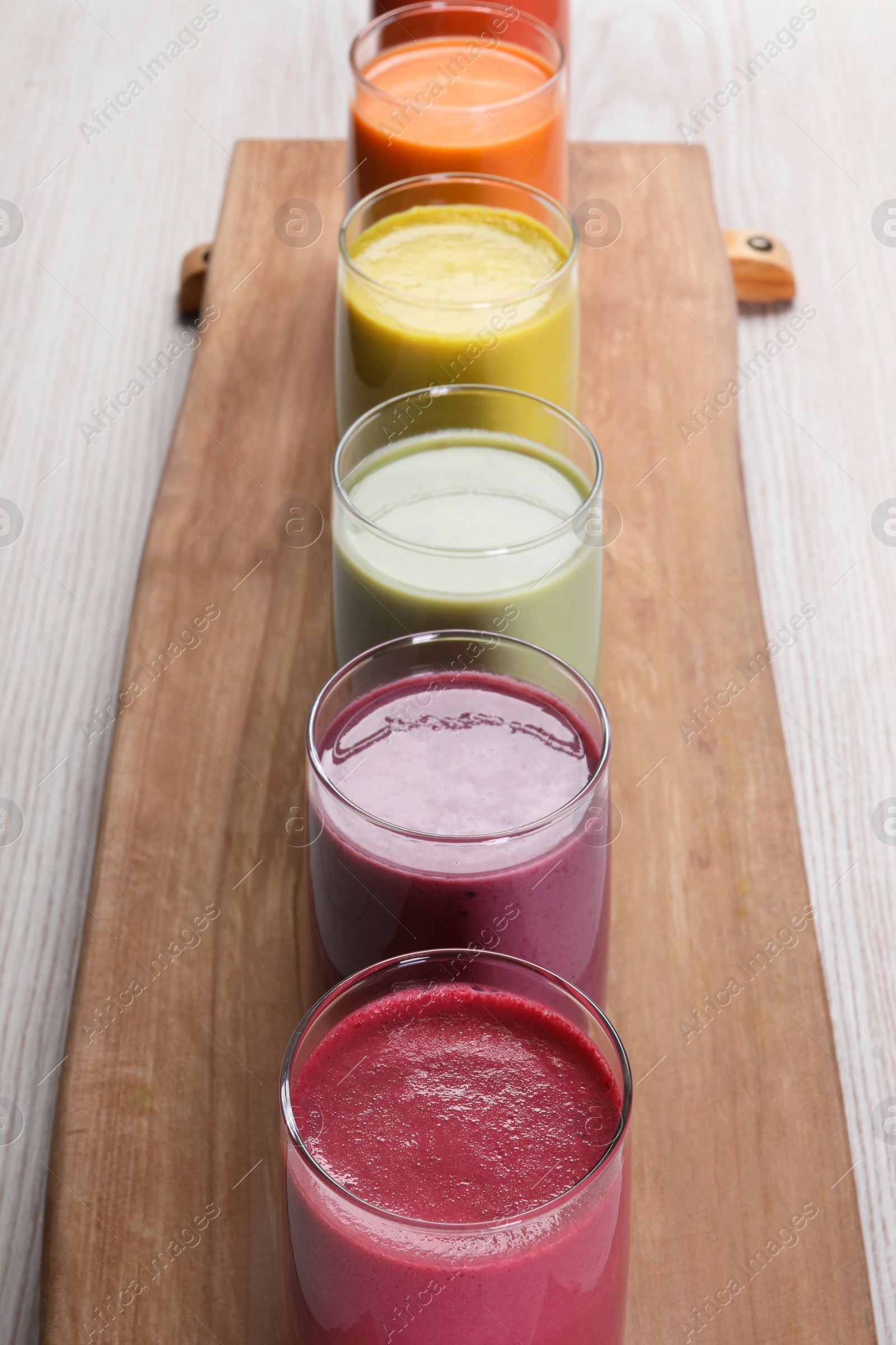 Photo of Board with many different tasty smoothies on white wooden table