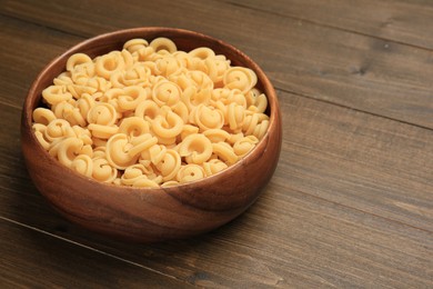 Photo of Raw dischi volanti pasta in bowl on wooden table, closeup