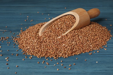 Photo of Wooden scoop with uncooked buckwheat on table