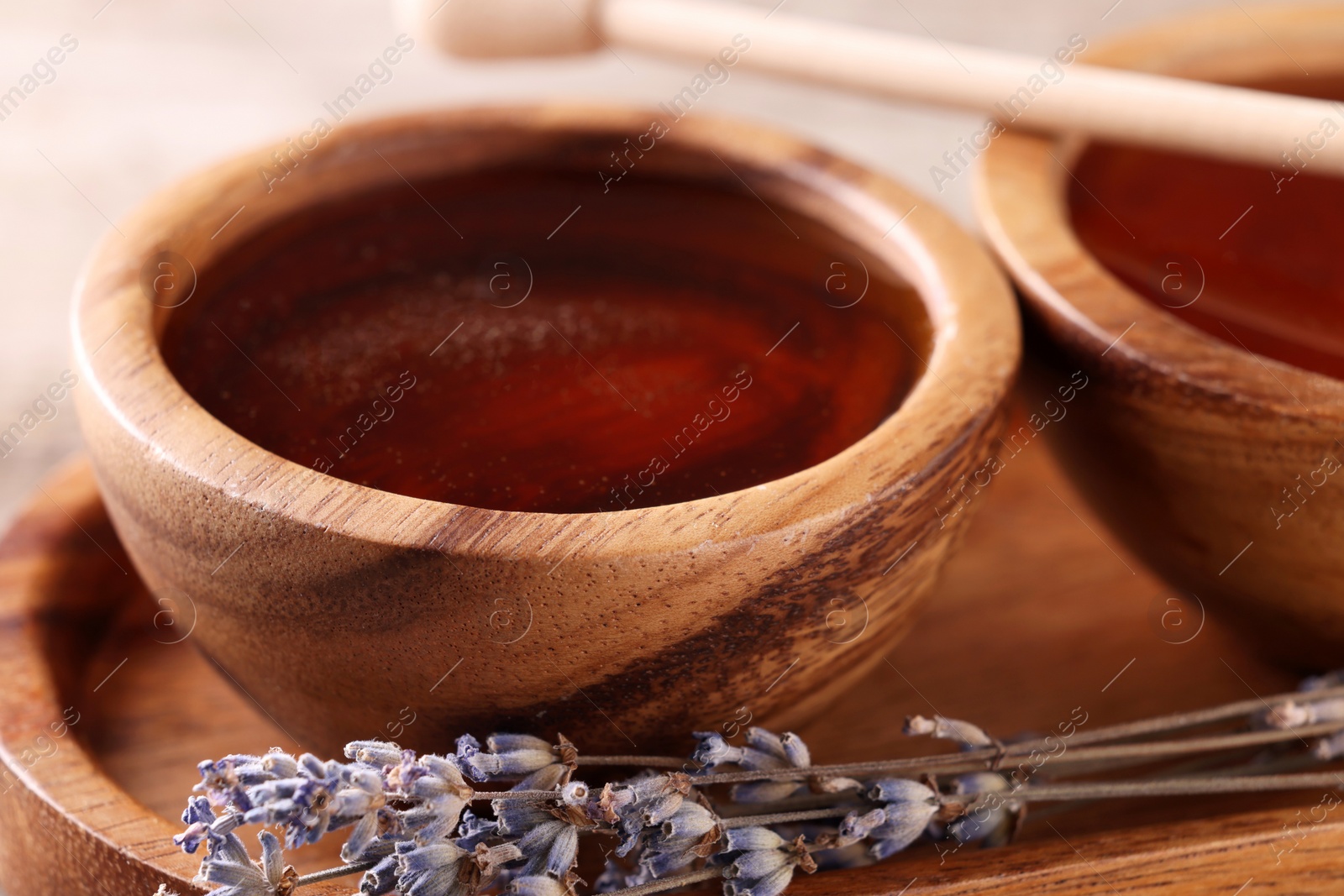 Photo of Delicious honey in wooden bowls and lavender flowers, closeup