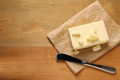 Tasty butter and knife on wooden table, top view. Space for text