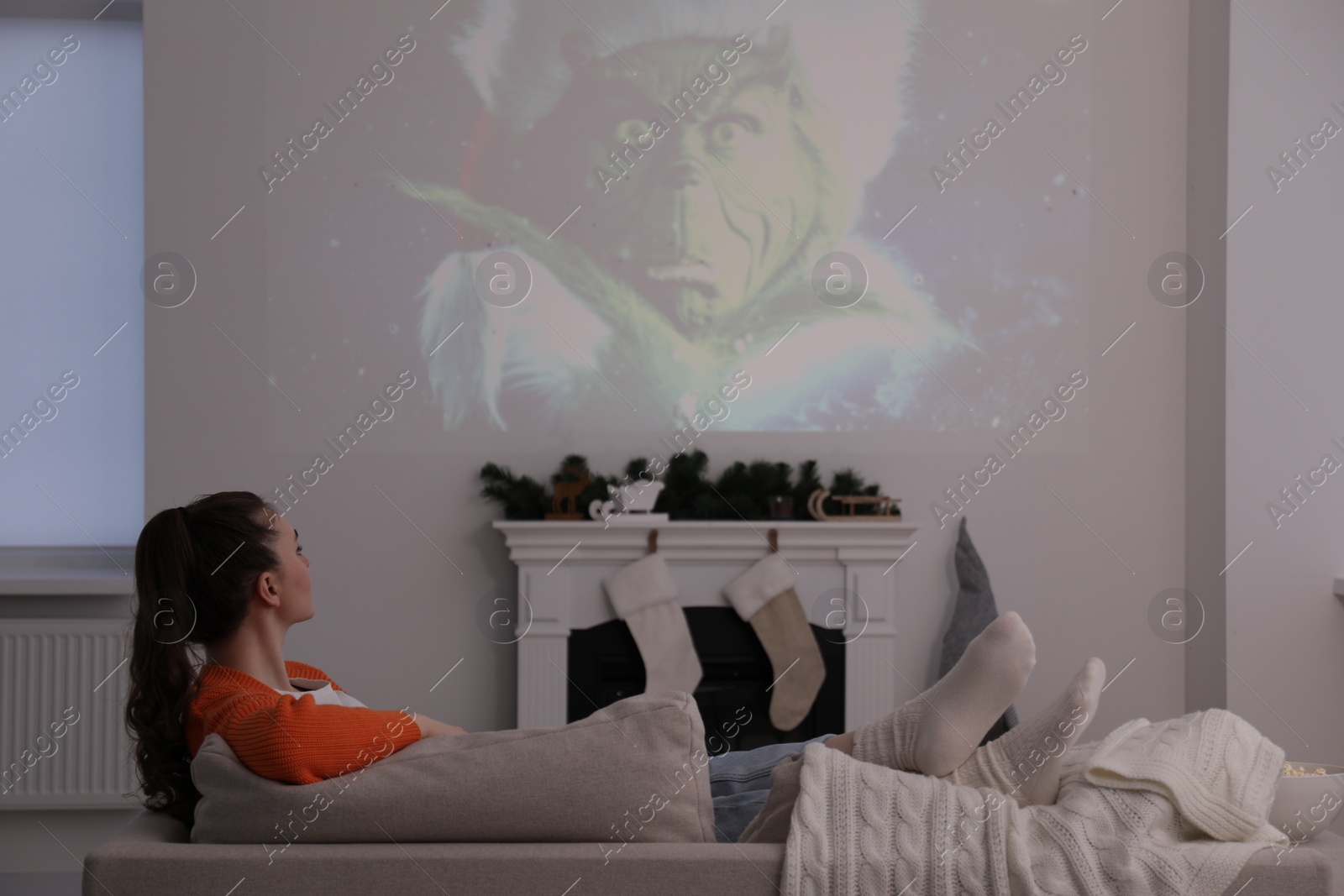 Photo of Lviv, Ukraine – January 24, 2023: Woman watching How the Grinch Stole Christmas movie via video projector at home