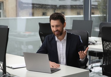 Man working on laptop at white desk in office