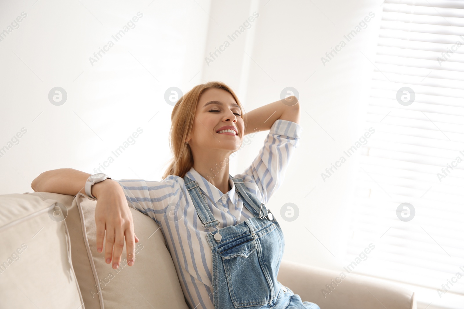 Photo of Young woman relaxing on couch near window at home