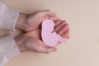 Photo of Female health. Woman holding newborn paper figure on beige background, top view
