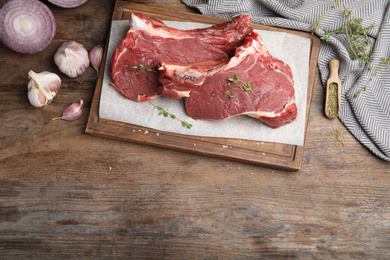 Photo of Flat lay composition with fresh beef cut on wooden table. Space for text