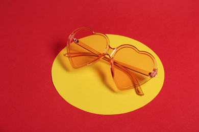 Stylish heart shaped glasses on color background