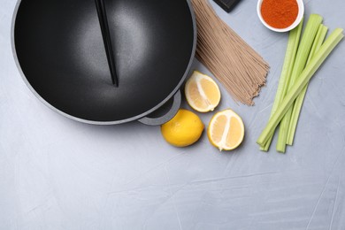 Photo of Wok, chopsticks and different products on grey table, flat lay. Space for text