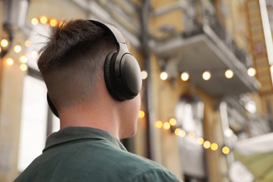 Photo of Man in headphones listening to music outdoors. Space for text