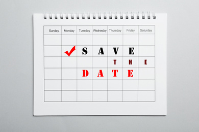 Blank calendar with phrase SAVE THE DATE on light grey background, top view