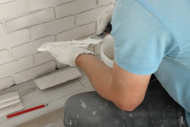 Photo of Worker installing decorative wall tiles in room, closeup