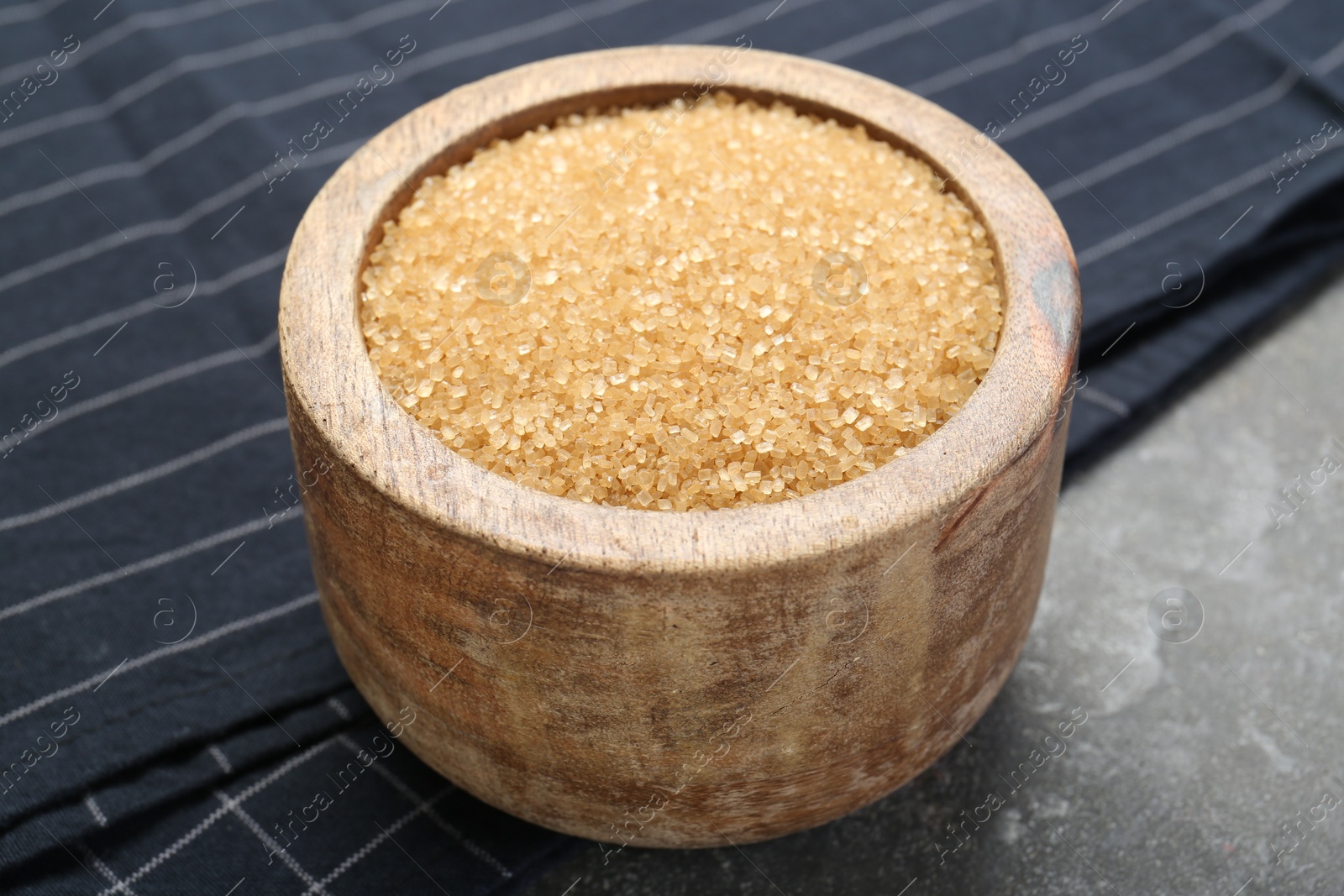 Photo of Brown sugar in bowl on grey textured table, closeup