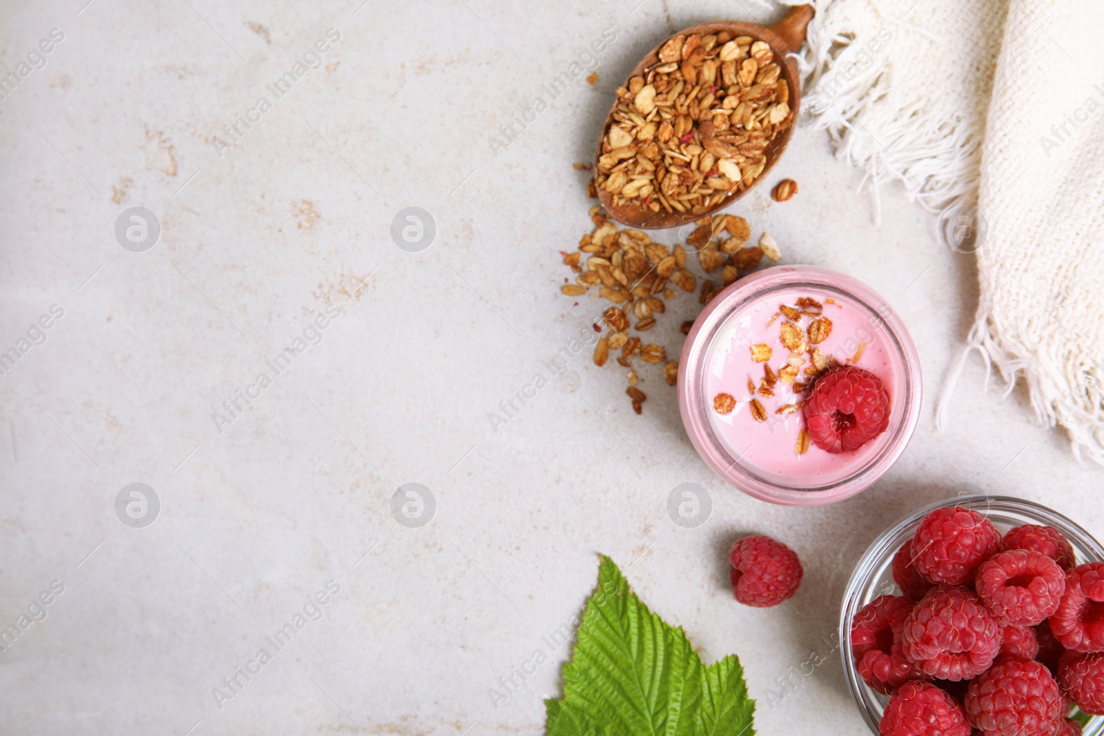 Photo of Tasty raspberry smoothie with granola in glass jar and fresh berries on light table, flat lay. Space for text