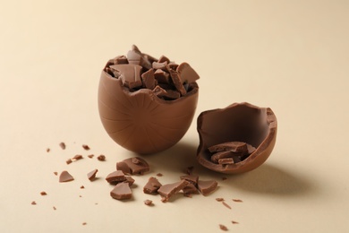 Photo of Broken milk chocolate egg on beige background