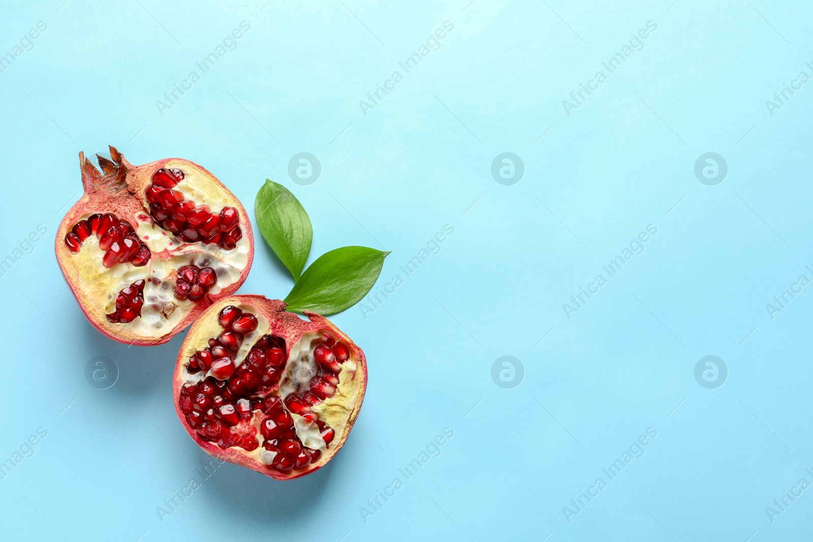 Photo of Ripe pomegranate halves on color background, top view with space for text