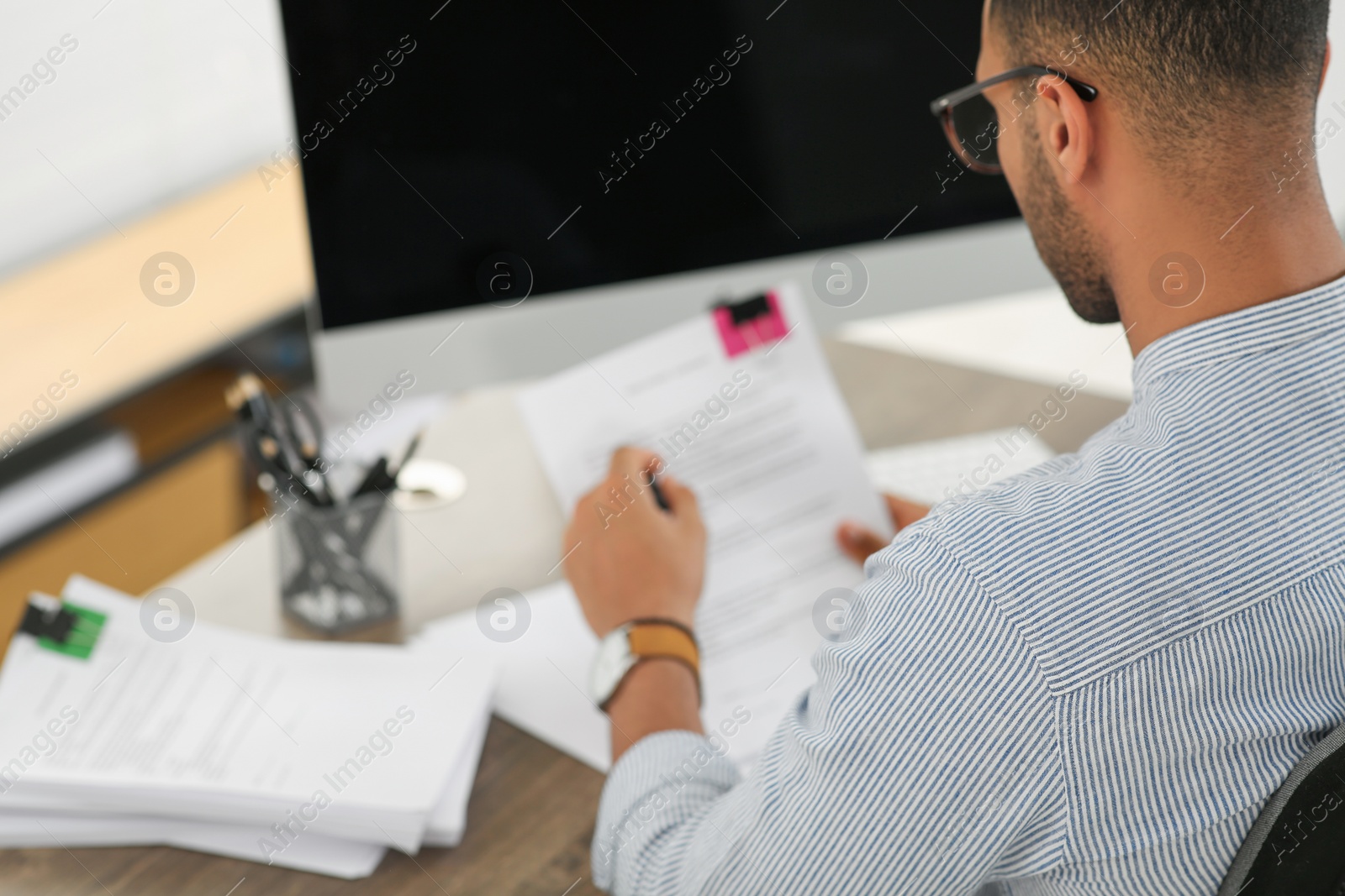 Photo of Man working with documents at wooden table in office, closeup