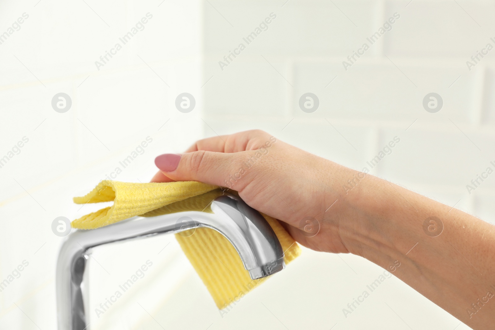 Photo of Woman cleaning tap with rag in kitchen, closeup