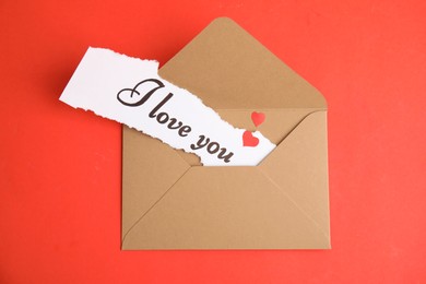 Photo of Sheet of paper with phrase I Love You in envelope on red background, top view