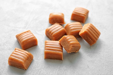 Delicious caramel candies on light background