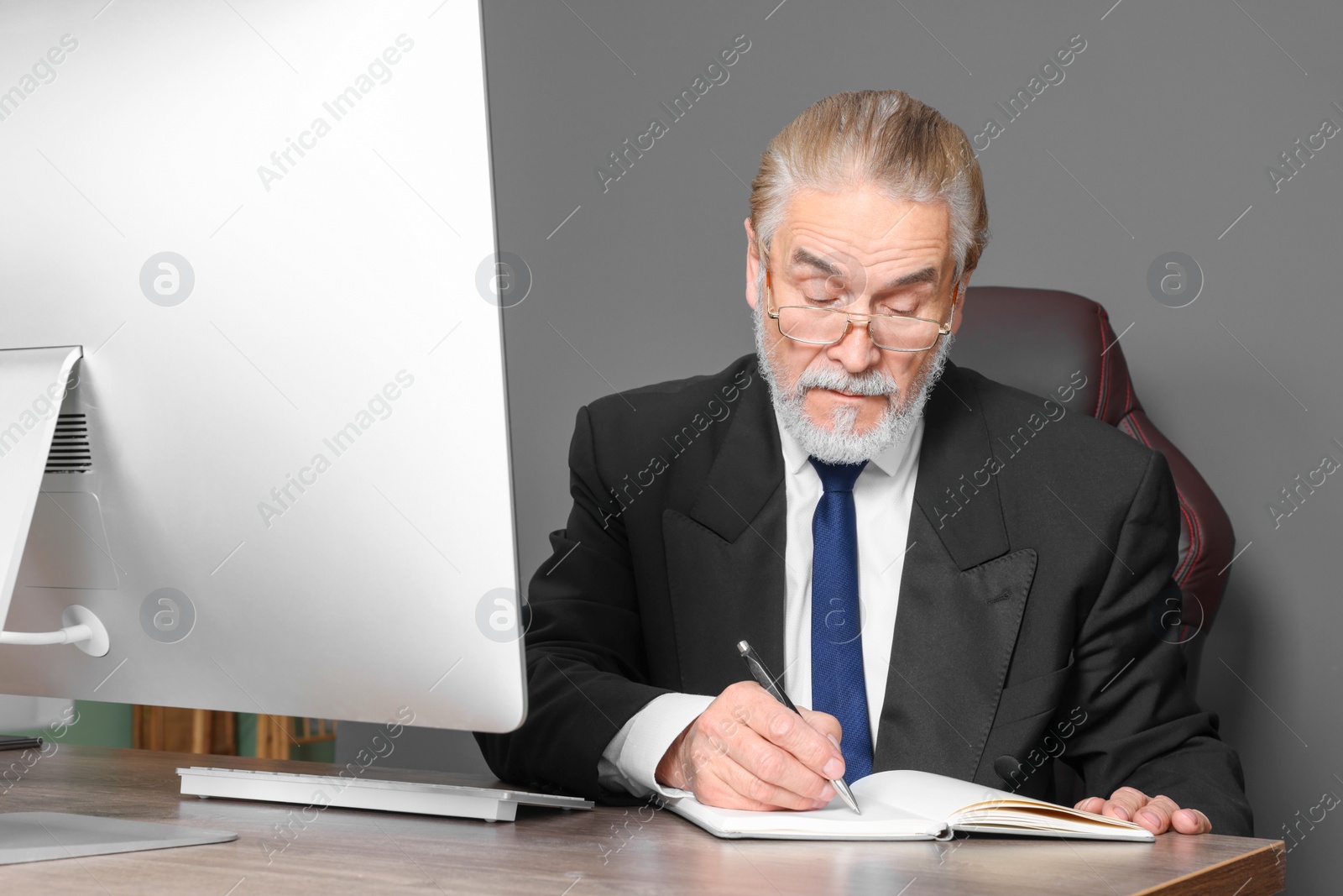 Photo of Senior boss working at wooden table in modern office