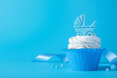 Beautifully decorated baby shower cupcake with cream and boy topper on light blue background. Space for text