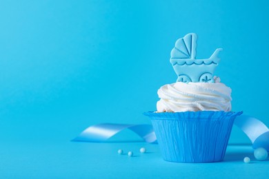 Photo of Beautifully decorated baby shower cupcake with cream and boy topper on light blue background. Space for text