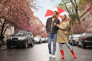Photo of Lovely couple with umbrella walking on spring day