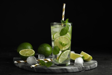 Delicious mojito and ingredients on black table