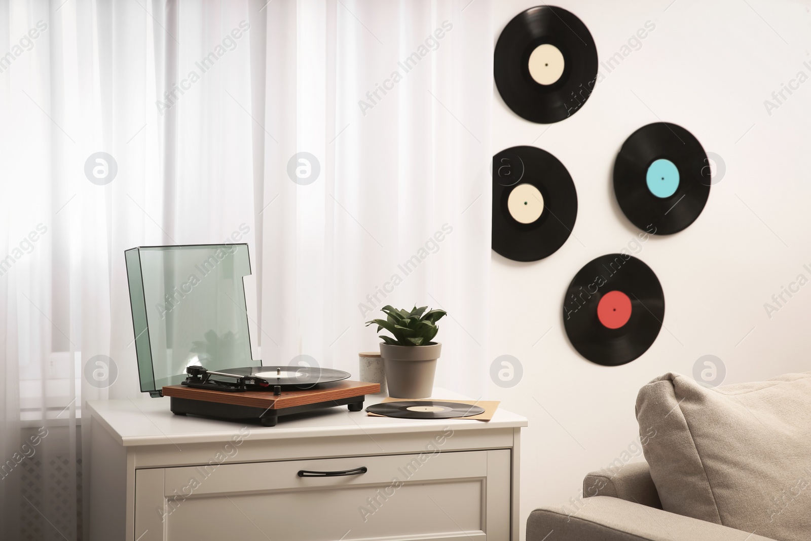 Photo of Stylish turntable on white chest of drawers and vinyl records indoors