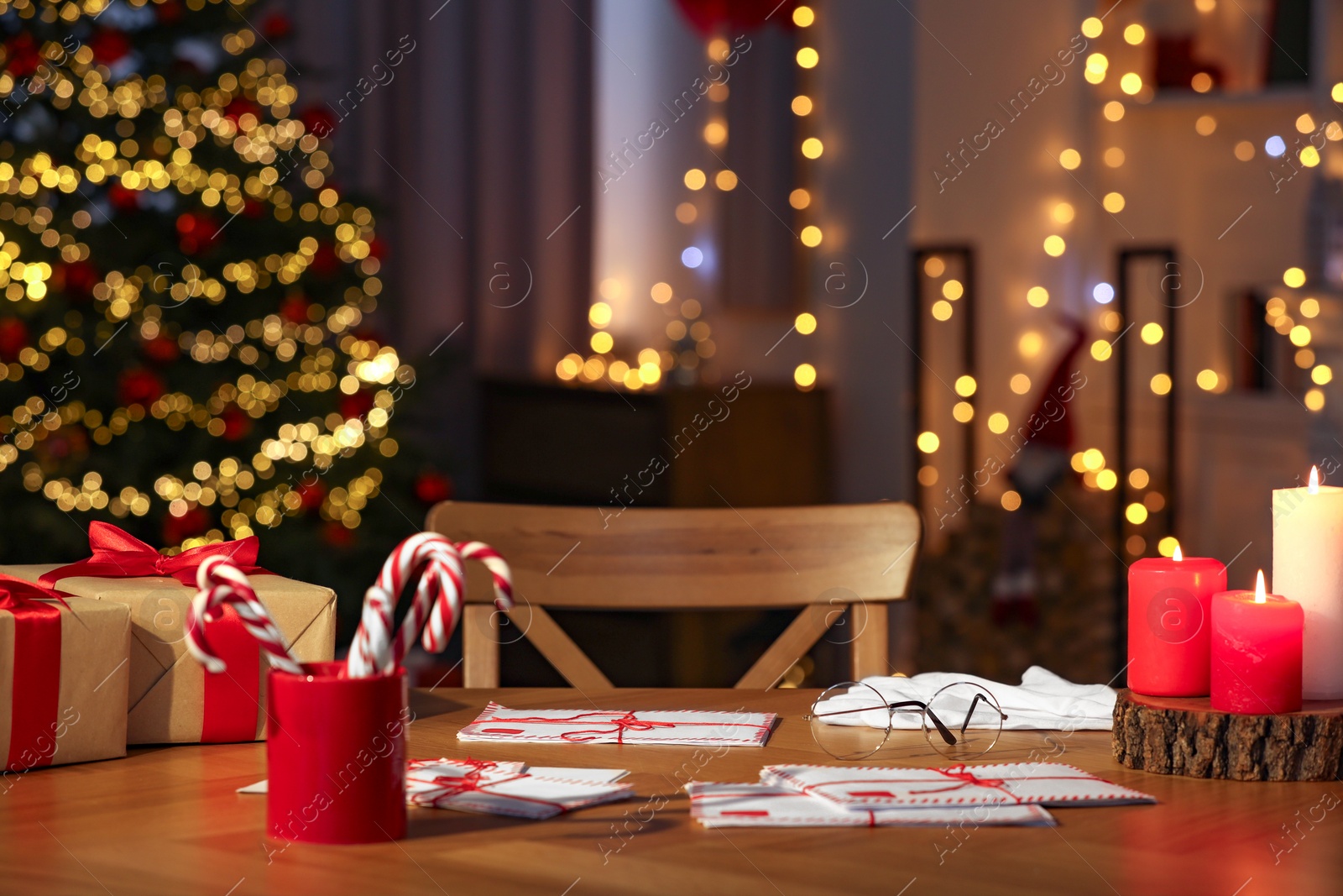 Photo of Santa's Claus workplace. Gift boxes, letters and candy canes on table in room with Christmas decor