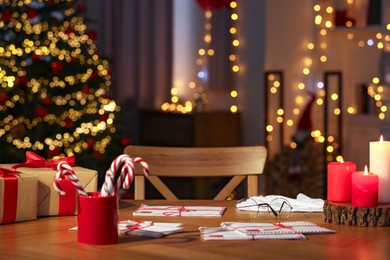 Santa's Claus workplace. Gift boxes, letters and candy canes on table in room with Christmas decor