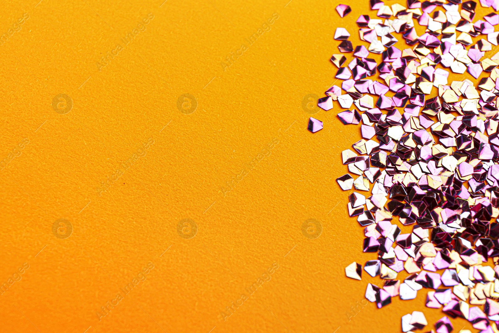 Photo of Shiny bright violet glitter on yellow background. Space for text