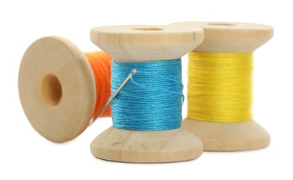 Photo of Different colorful sewing threads with needle on white background, closeup