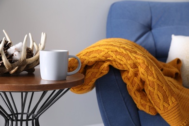 Soft knitted blanket on armchair indoors, closeup. Home interior