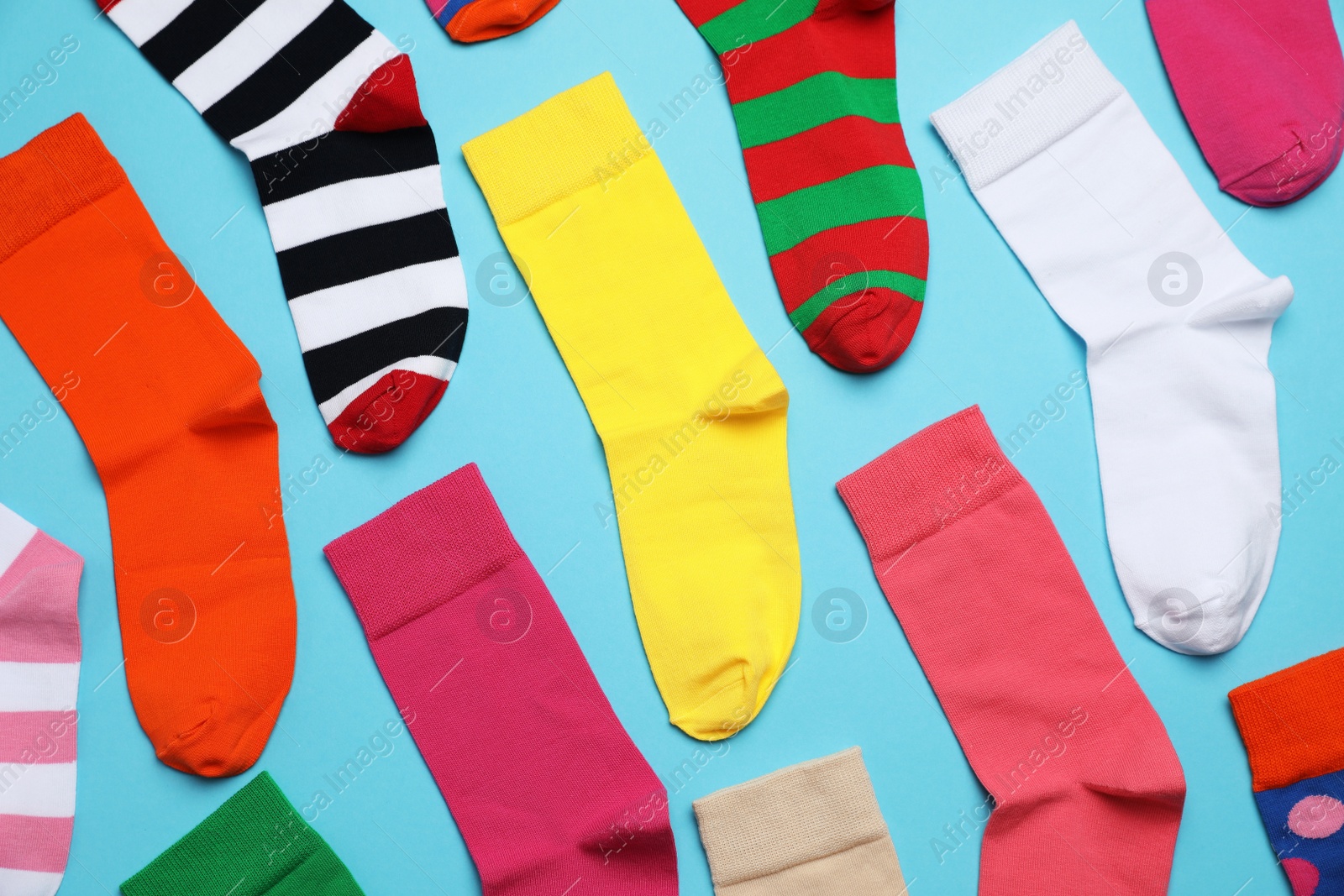 Photo of Many different colorful socks on light blue background, flat lay