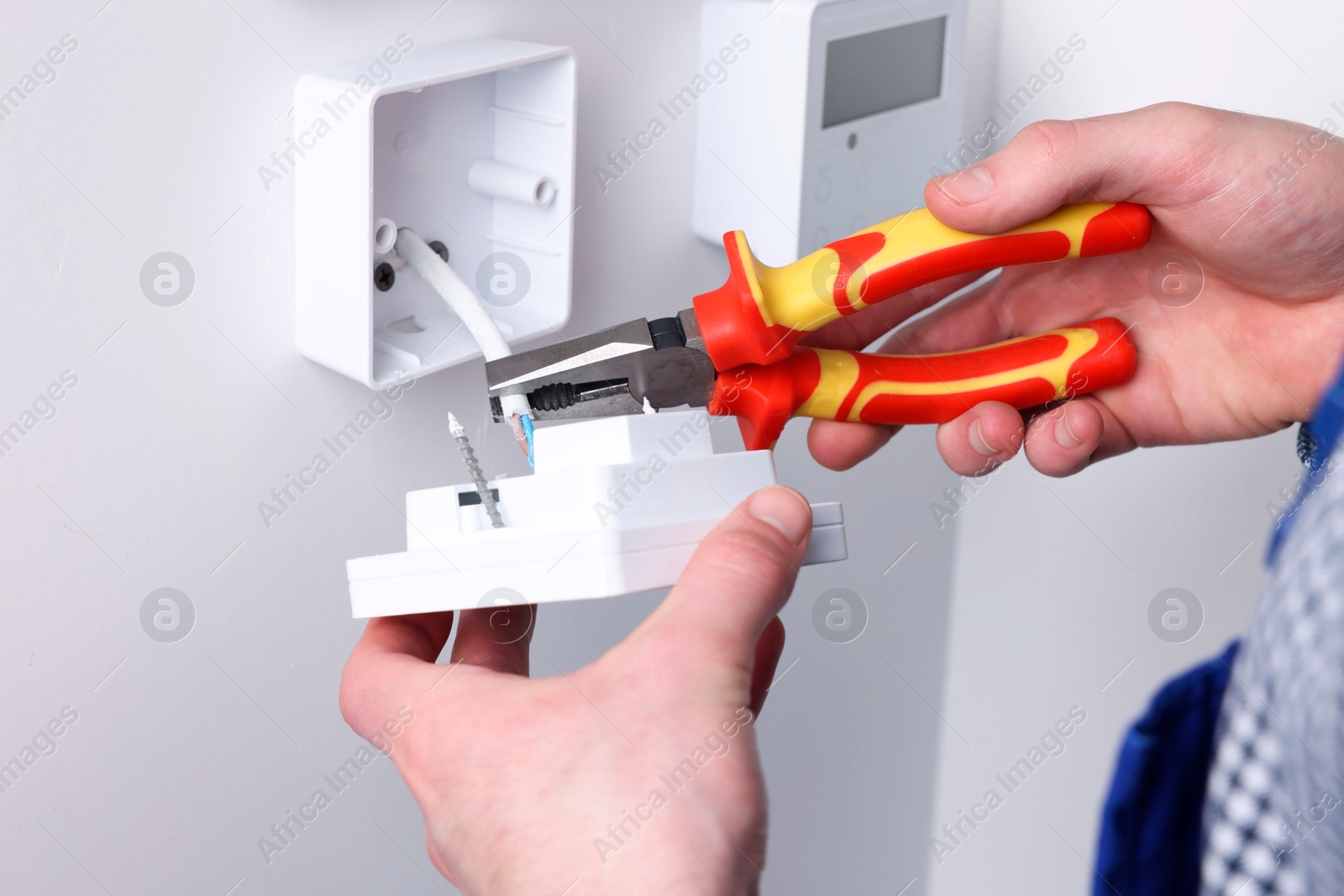 Photo of Professional repairman fixing electric house appliance with pliers indoors, closeup