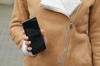 Photo of Woman showing damaged smartphone outdoors, closeup. Device repairing