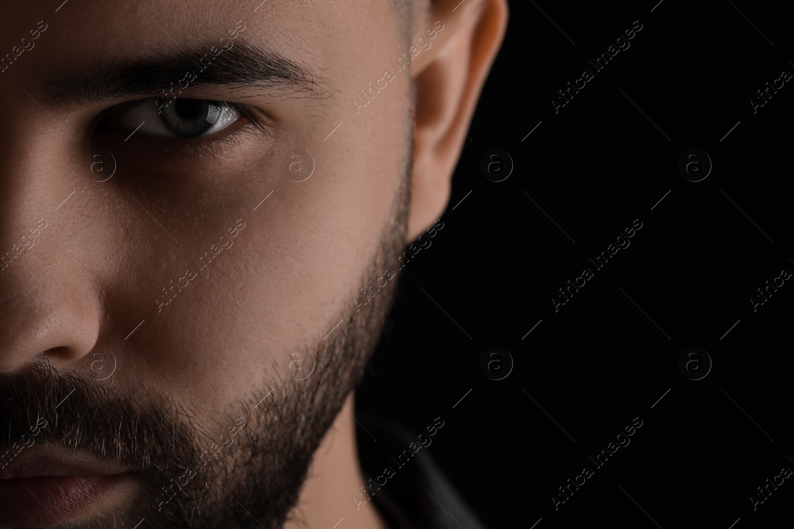 Photo of Evil eye. Man with scary eyes on black background, space for text
